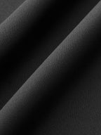 Close-up of black jumpsuit’s fine, textured weave, with soft folds, shadows, and highlights.