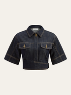 Cropped dark denim top with collar, front zipper, chest pockets, gold buttons, tan stitching.