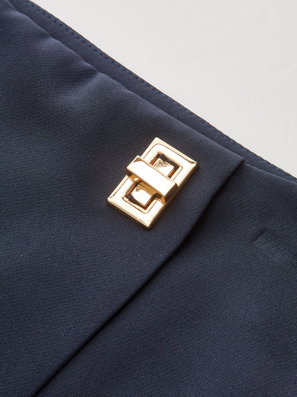 Navy blue asymmetrical skort featuring a shiny gold rectangular buckle and metallic accent.