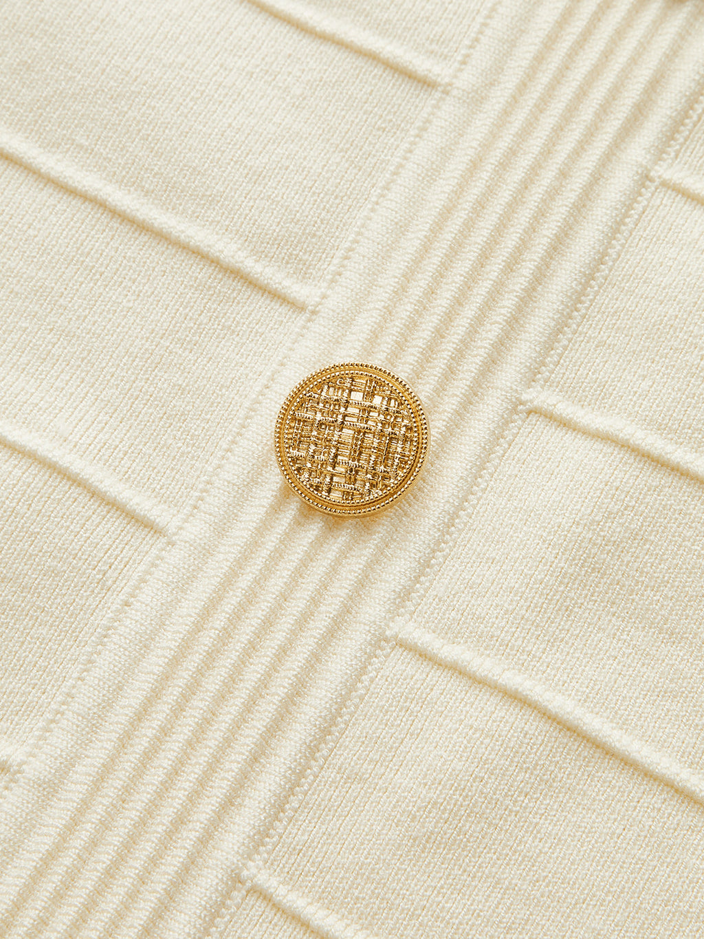 Cream stretch knit backless halter dress with vertical ribs and a single gold neck button.