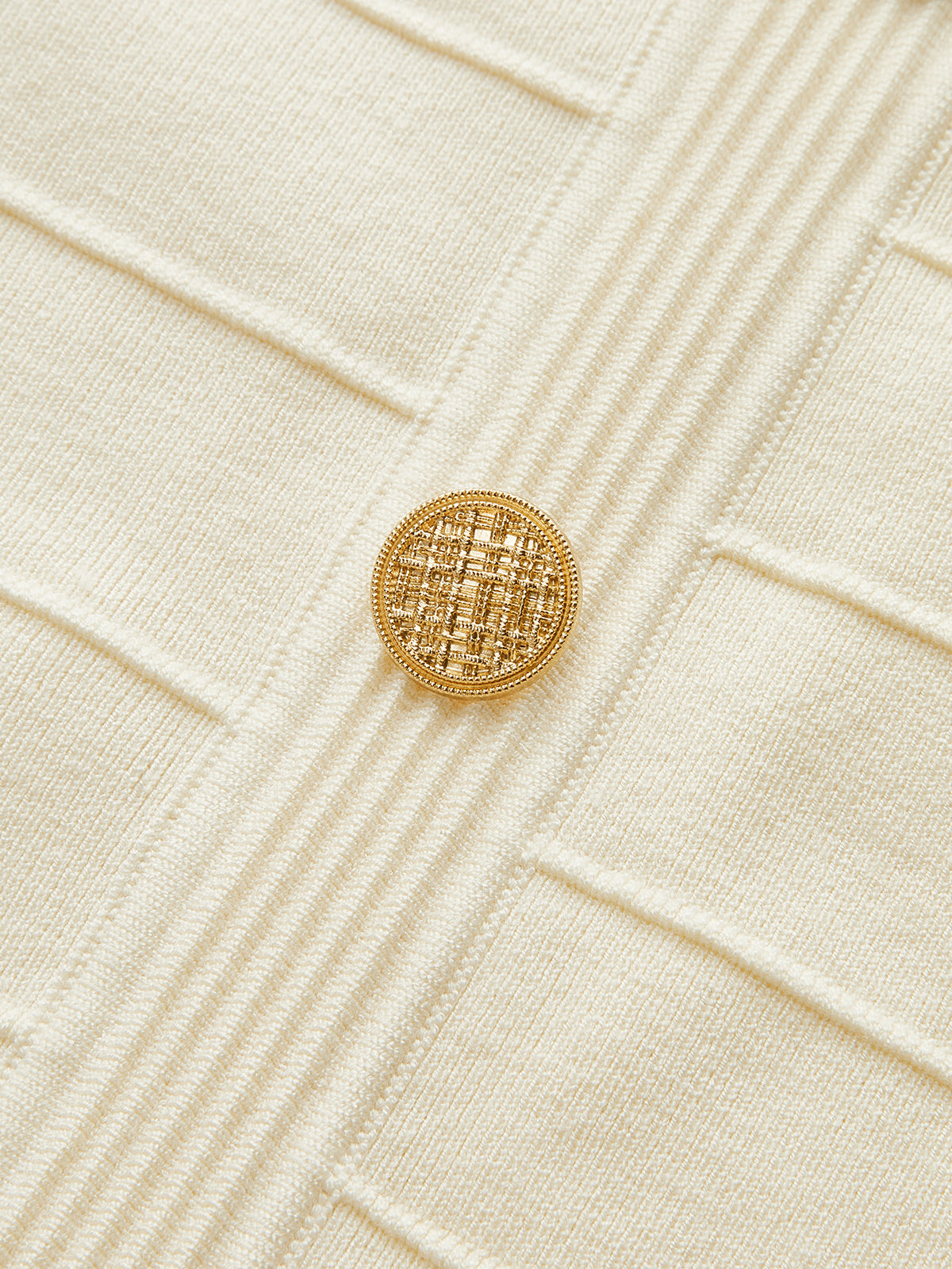 Cream stretch knit backless halter dress with vertical ribs and a single gold neck button.