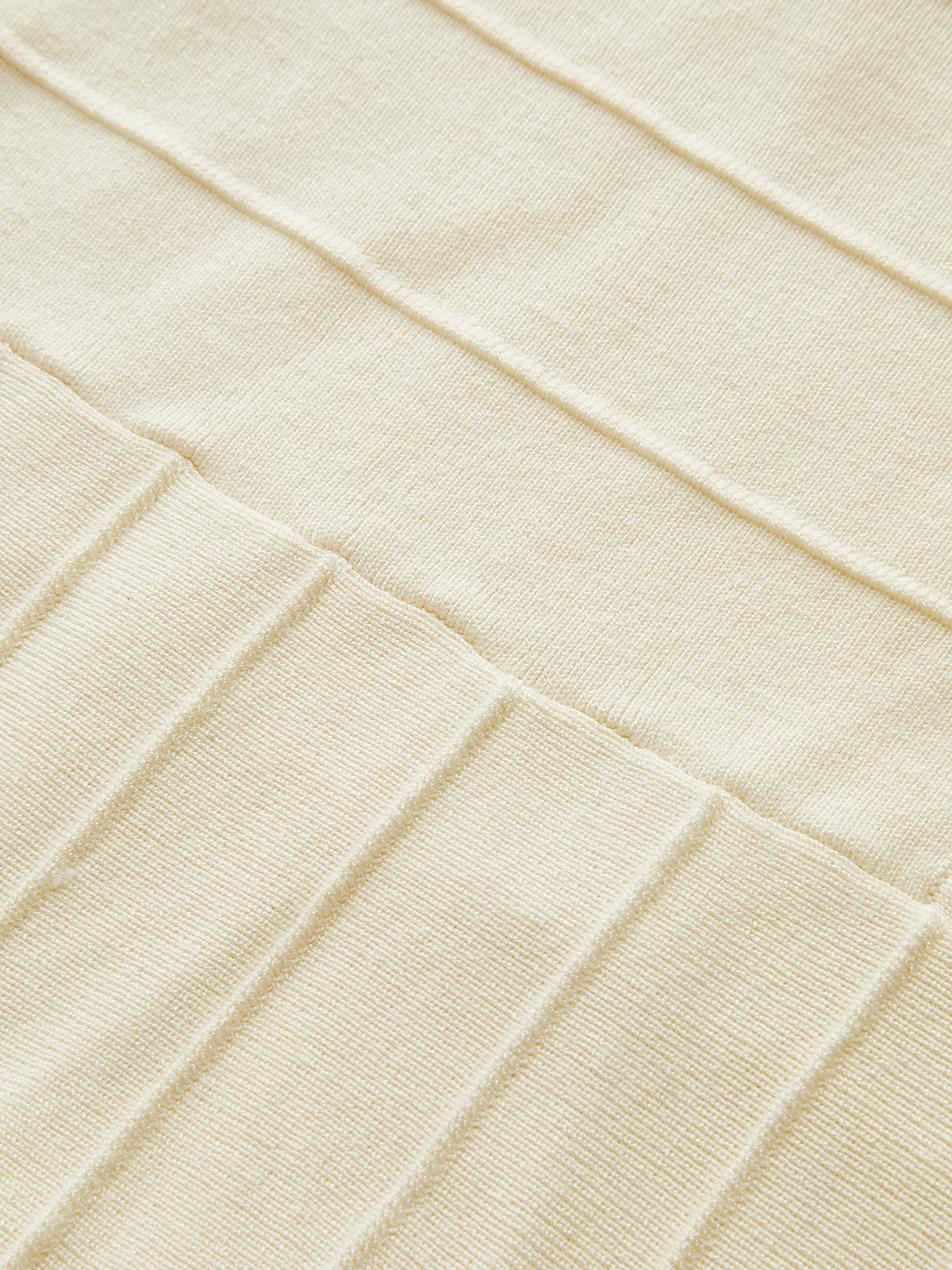 Beige ribbed knit dress with neck detail, highlighting textured fabric and intricate stitching.
