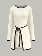 Cream knit mini wrap sweater dress with long sleeves, black trim, and a black tie belt.