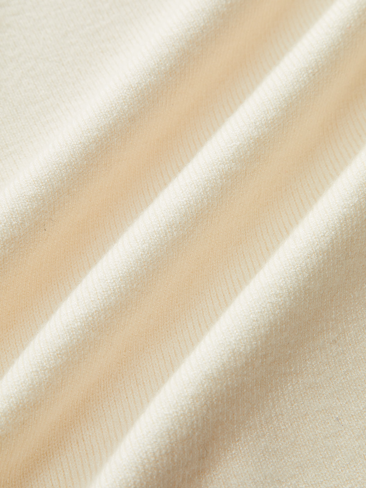 Cream-colored sweater dress with long sleeves, soft texture, subtle folds, and contrast trim details.