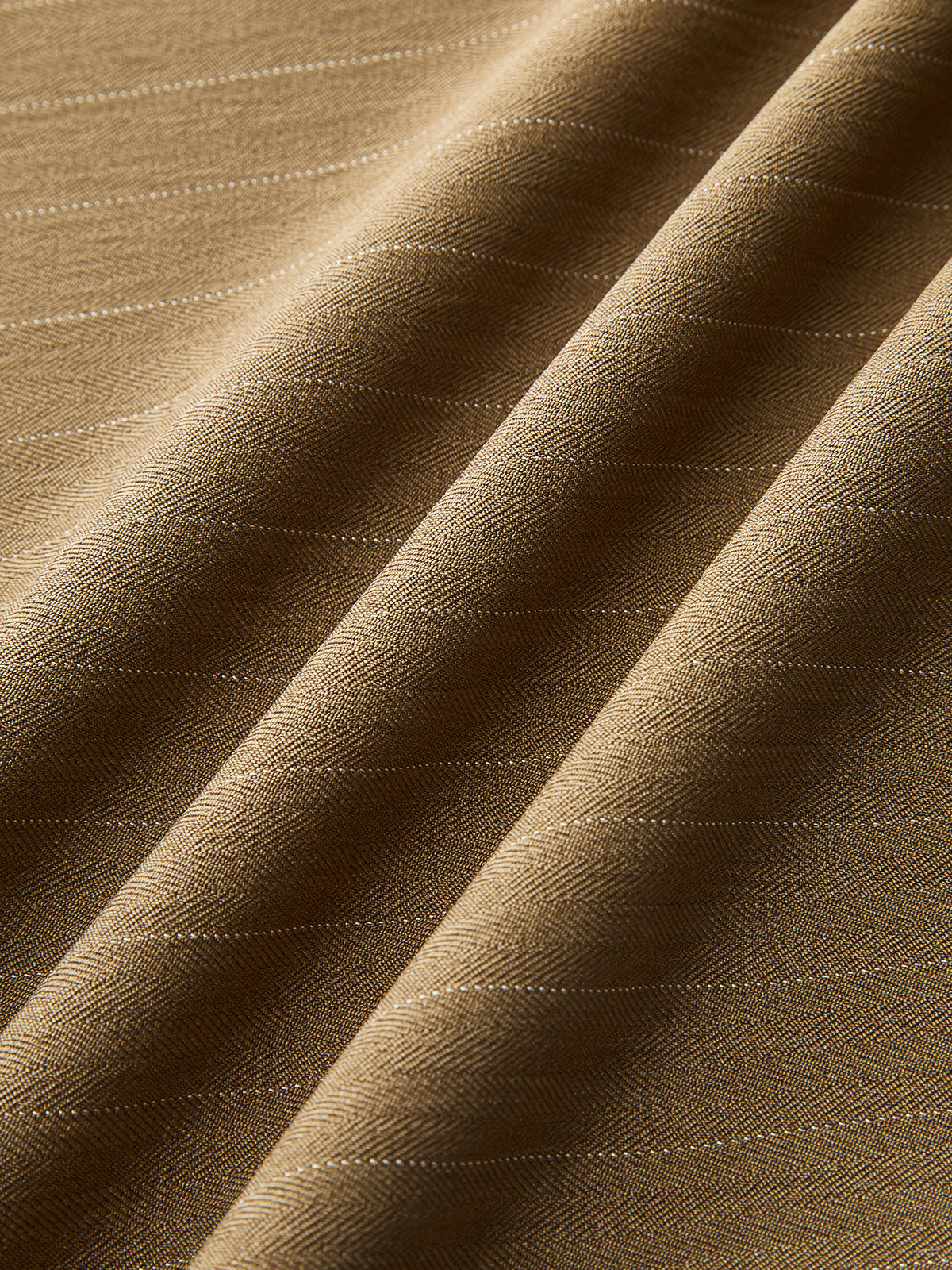 Wide-leg brown pleated trousers with diagonal herringbone, fine pinstripes, and softly draped folds.