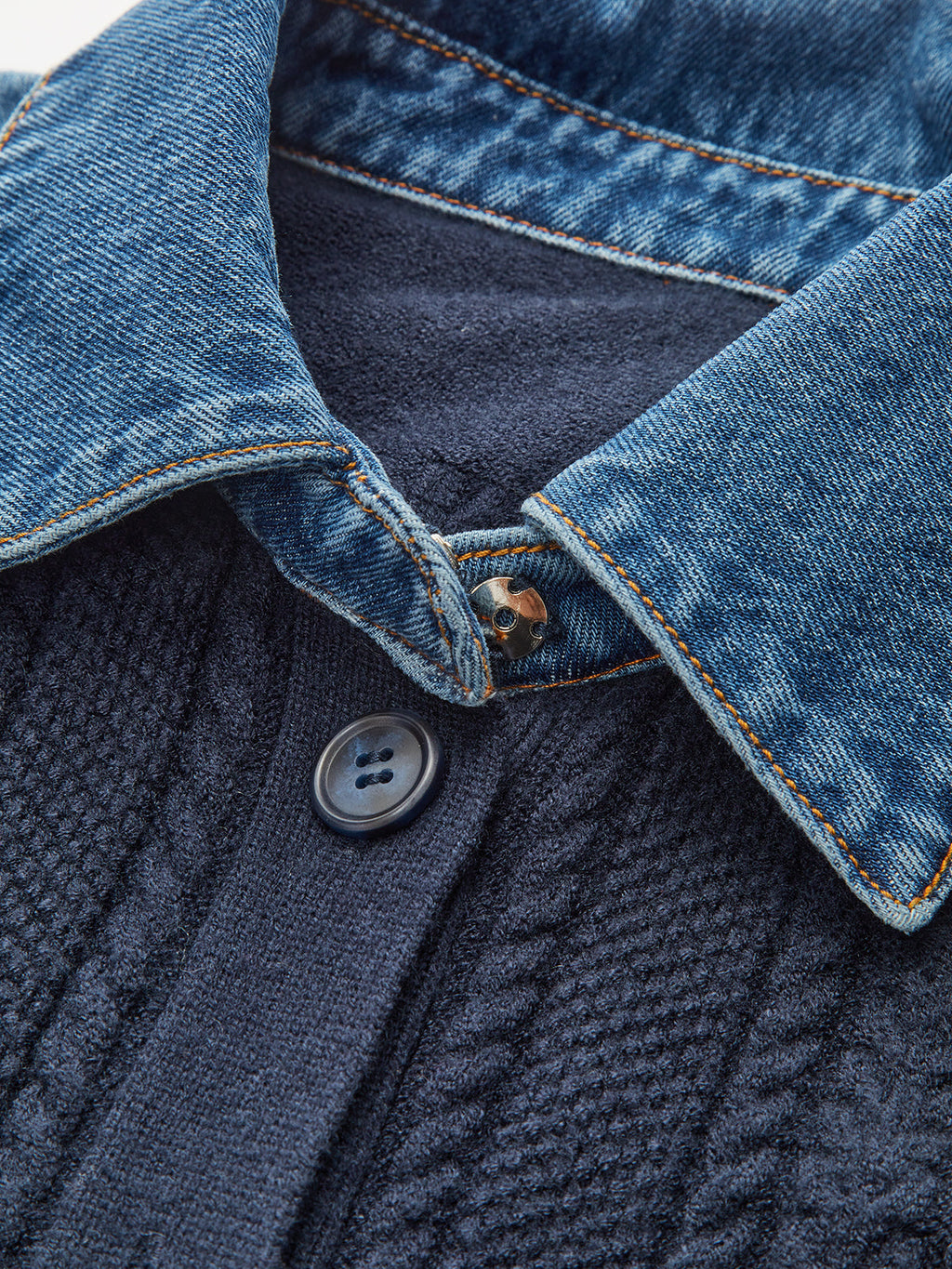Close-up of Denim Collar Peplum Cardigan with cable knit detail, black button, fine stitching.