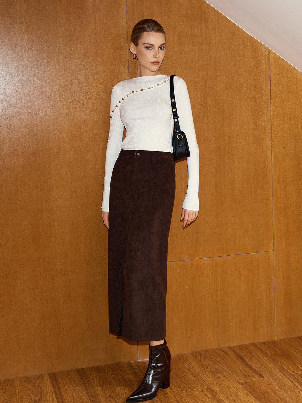 An asymmetric wool blend top with metal detail, cut-outs, and a dark brown midi skirt.