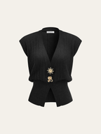 A black ribbed knit vest with metallic details, cap sleeves, and two gold pins at waist.
