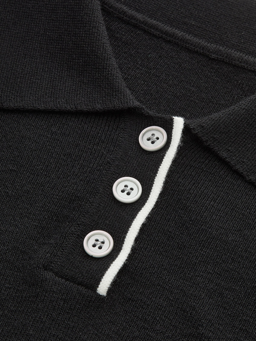Slim-fit black knit polo crop with collar, white contrast trim, and three white buttons.