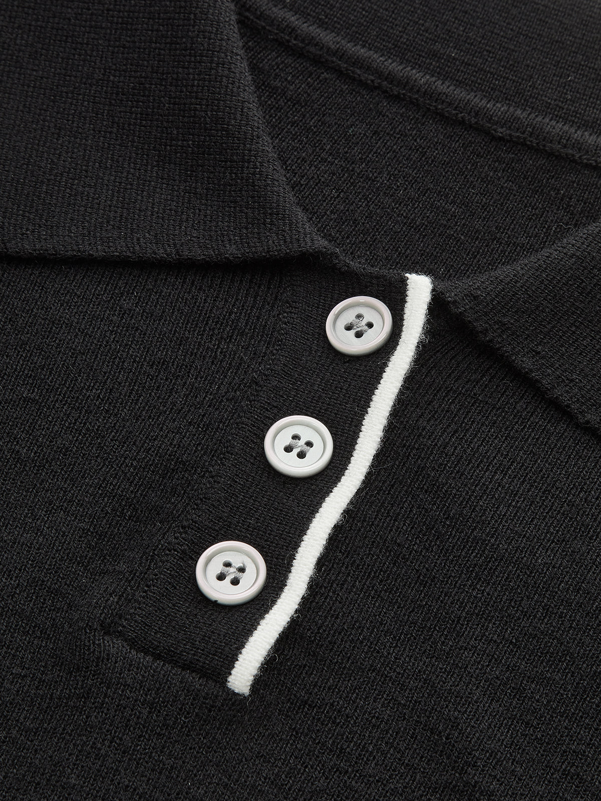 Slim-fit black knit polo crop with collar, white contrast trim, and three white buttons.