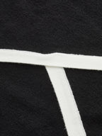 Black asymmetric wool blend polo crop with T-shaped white trim and textured knit fabric.