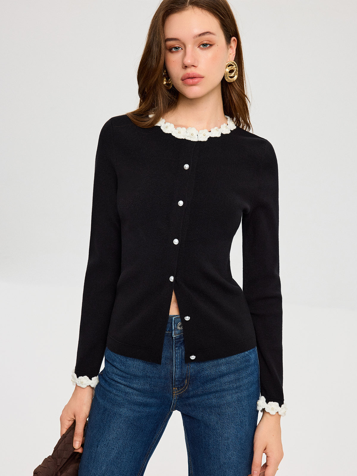 A 3D floral embroidered cardigan with elegant pearl buttons, paired with classic blue jeans.