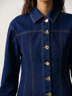 A 100 cotton fitted denim jacket with metal buttons, prominent stitching, and a pointed collar.