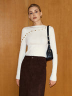 Asymmetric wool blend top with metal detail and cut-out design, paired with dark brown skirt.