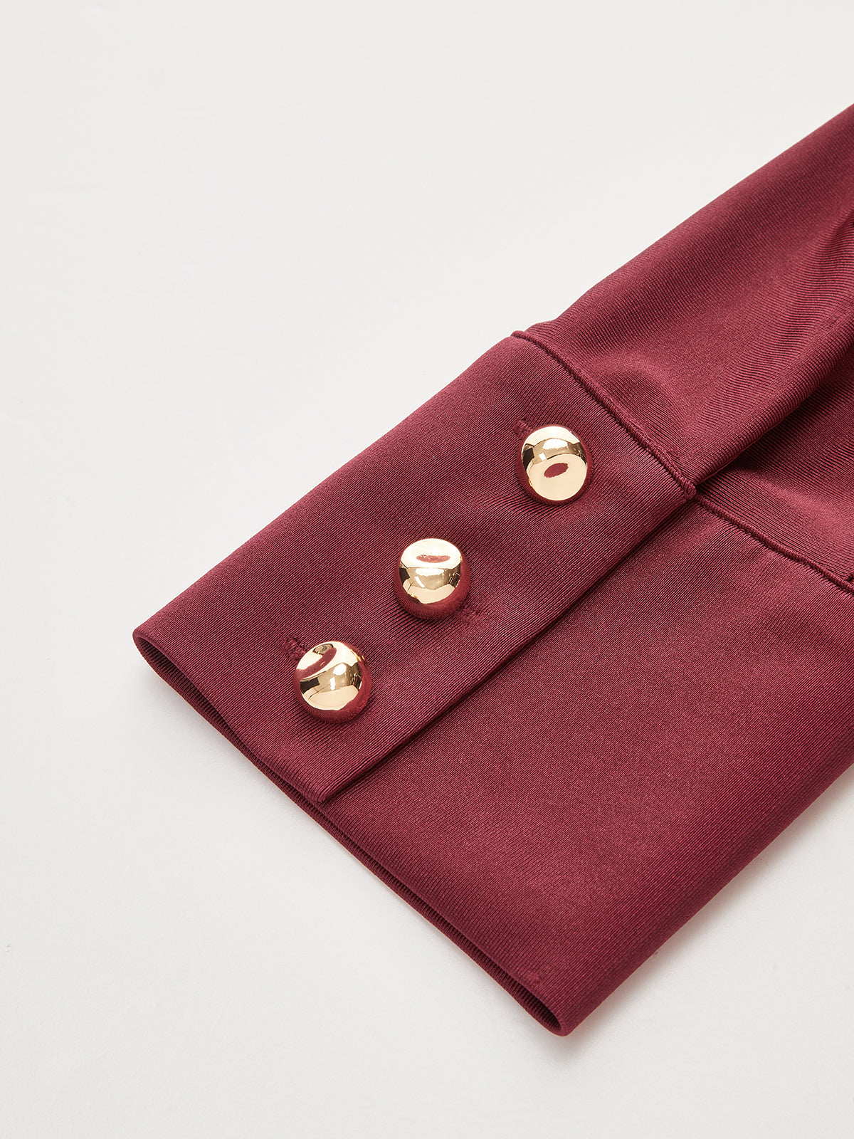 Long sleeve bodysuit with collar and cuffs, featuring three shiny gold buttons.