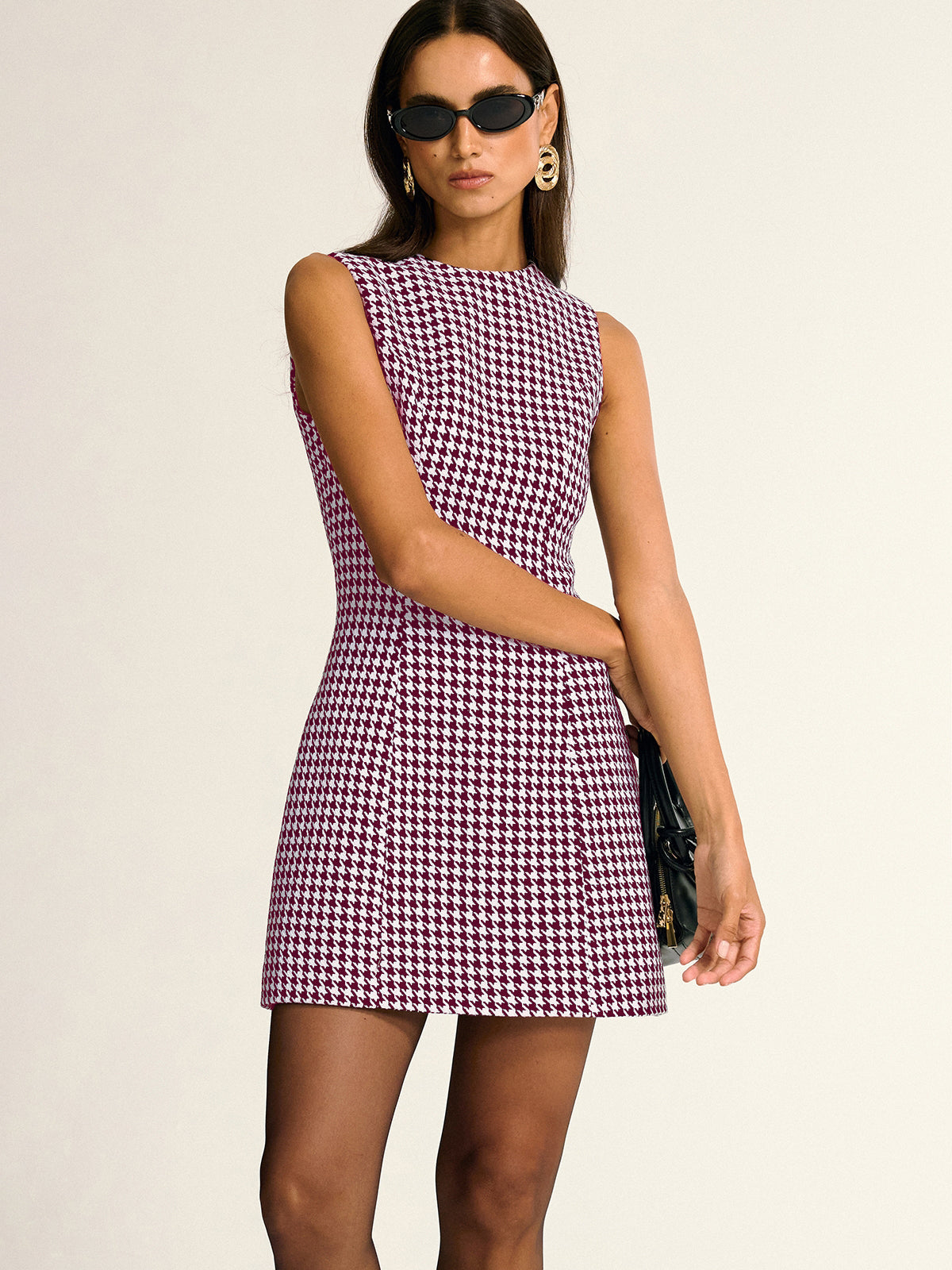 Sleeveless A-line mini dress with a chic houndstooth pattern in black and white.