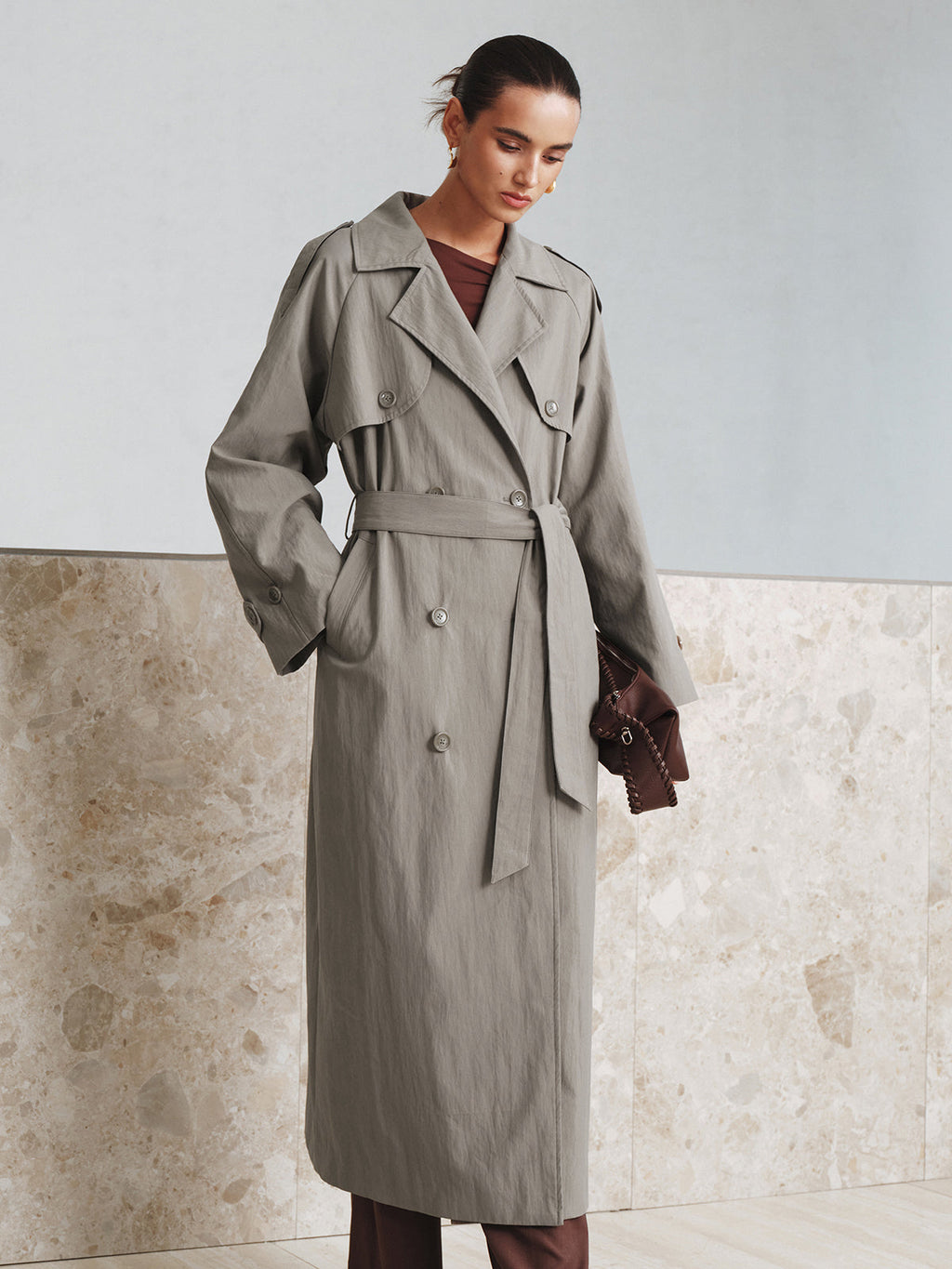 A grey, double-breasted Belted Cotton Oversize Trench Coat by LA FINE FLEUR, cinched waist.