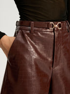 LA FINE FLEUR's belted faux leather shorts and black sheer long-sleeve top.