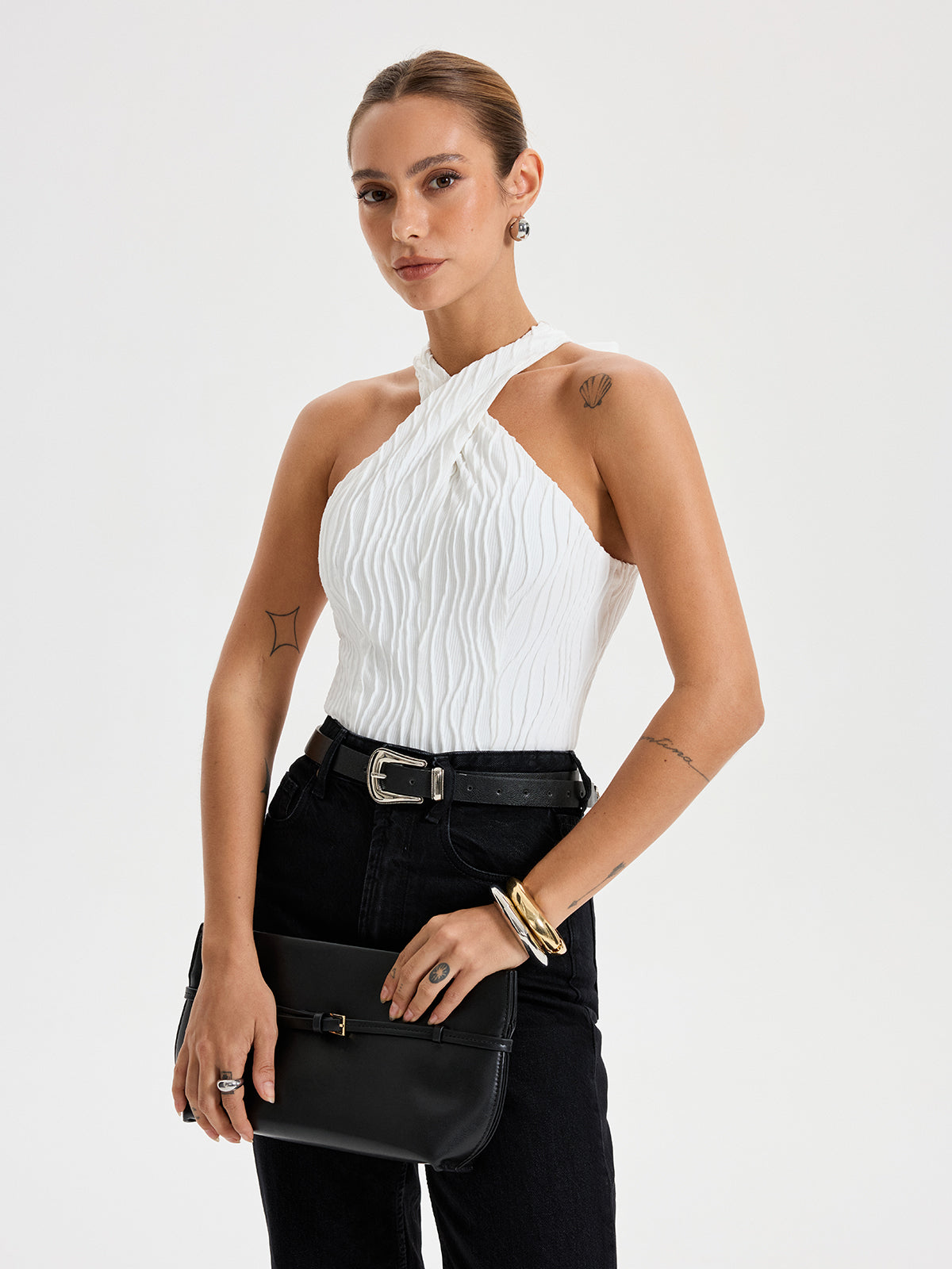 Crisscross textured halter neck top paired with high-waisted black jeans.