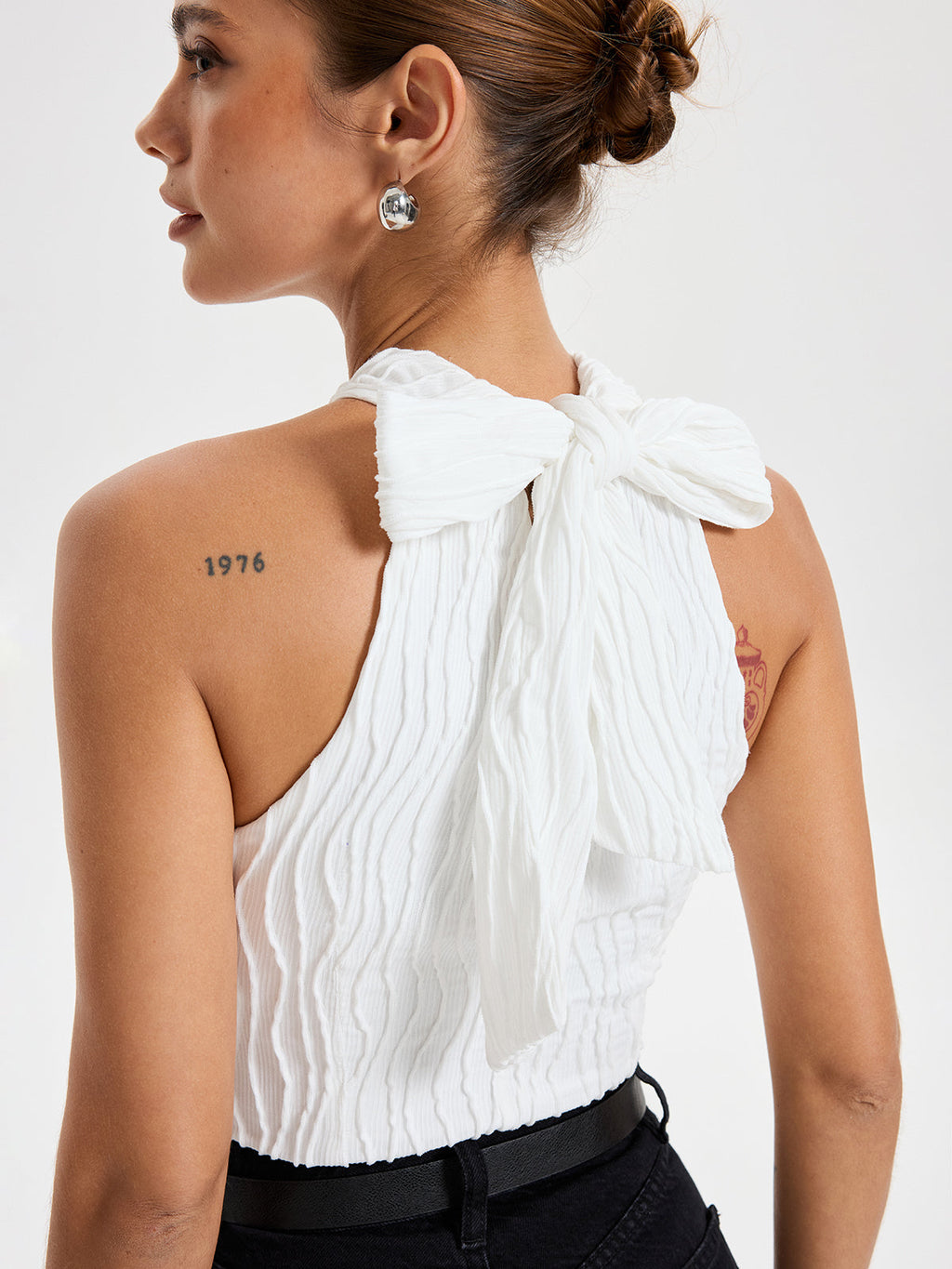 White BYPINKYPARIS crisscross textured halter neck top with a large bow at neck.