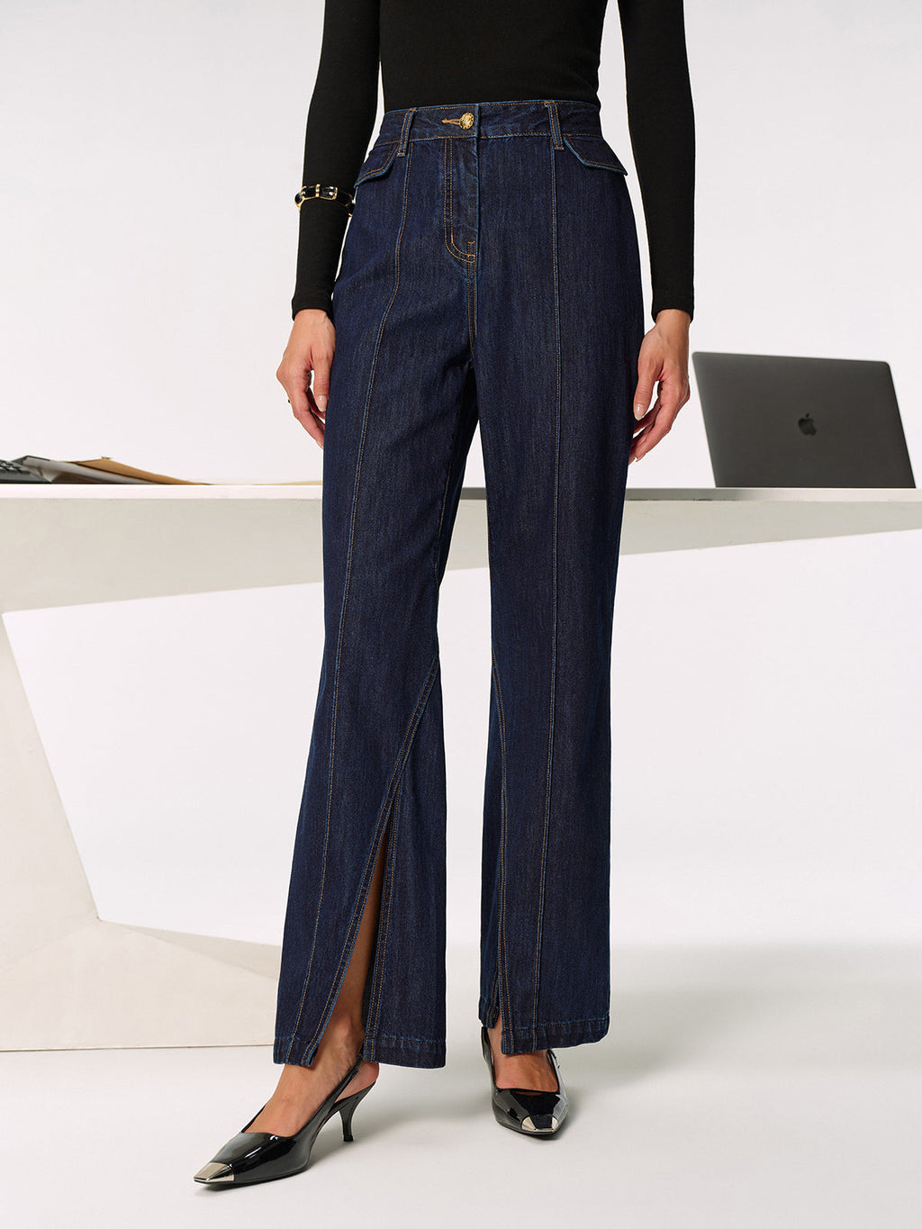 LA FINE FLEUR’s mid-rise jeans with chic side slits, black long-sleeve top, heels.