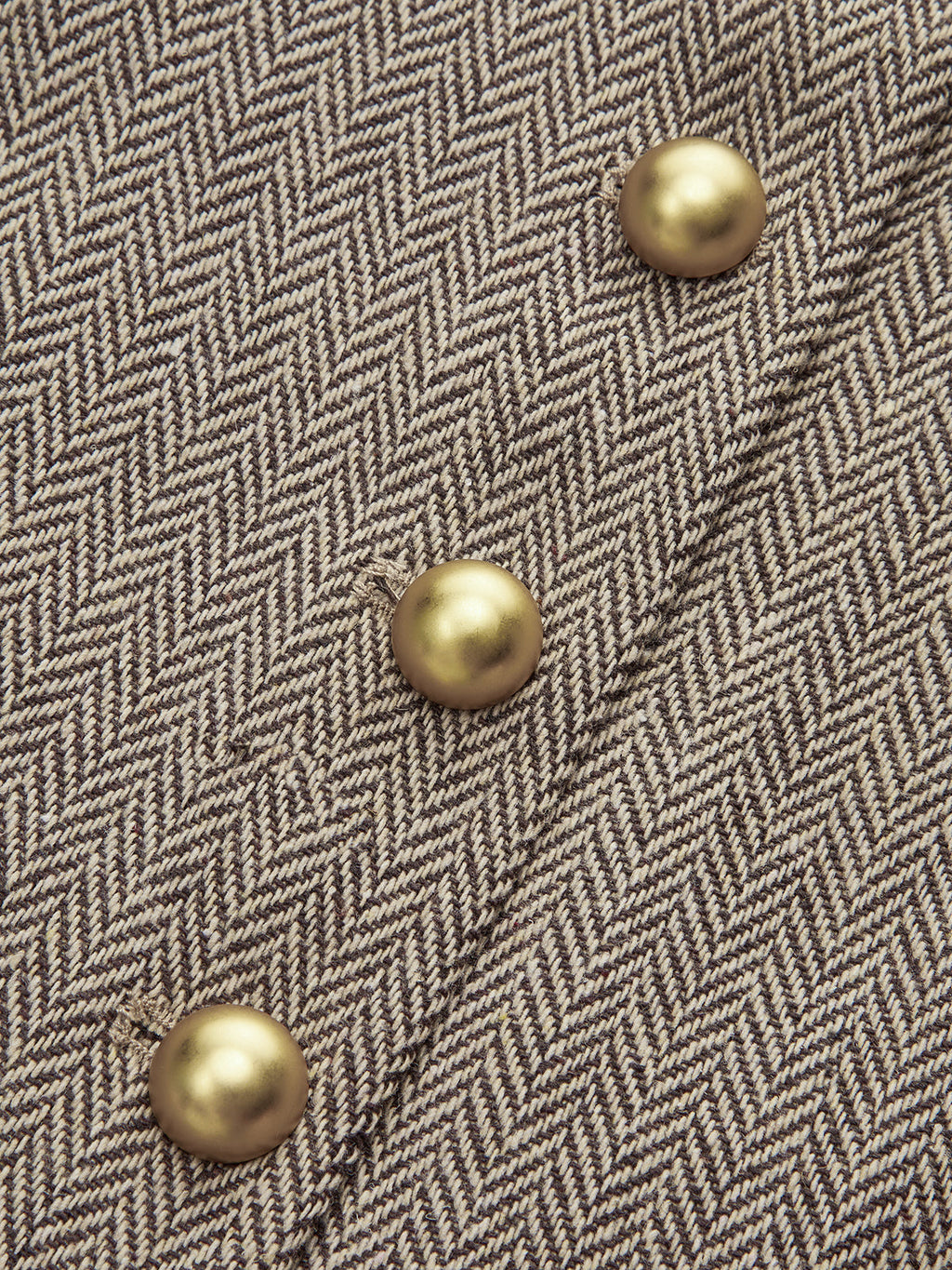 Beige and brown plaid mini dress with pleated skirt and four diagonal gold snap buttons.