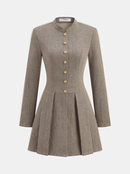 A plaid mini dress with pleated skirt, long sleeves, snap buttons, and mandarin collar.