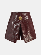 Rose gold faux leather mini skort with front overlay panel and gold floral-shaped button.
