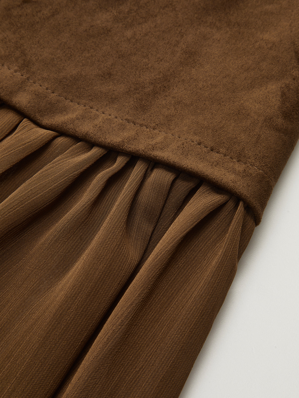 Brown suede-style long skirt with textured band, sheer mesh accents, and flowing pleats.