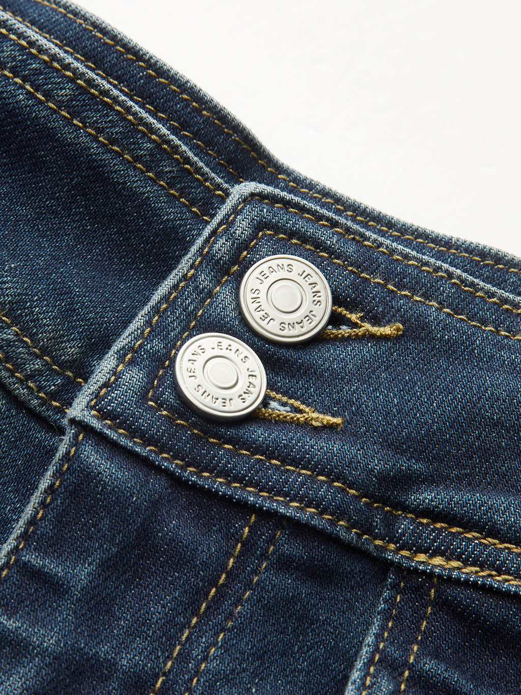 Close-up of LA FINE FLEUR high-waist flared jeans waistband with double buttons, yellow stitching.