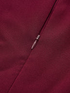 Burgundy sleeveless mini dress with asymmetric ruffle hem, woven texture, tailored seams, concealed zipper.