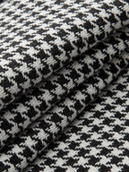 Black and white houndstooth pleated wide leg pants featuring distinctive button details throughout.