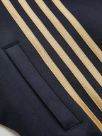 Black cropped athletic sweatshirt with four gold stripes and a rectangular pocket on front.