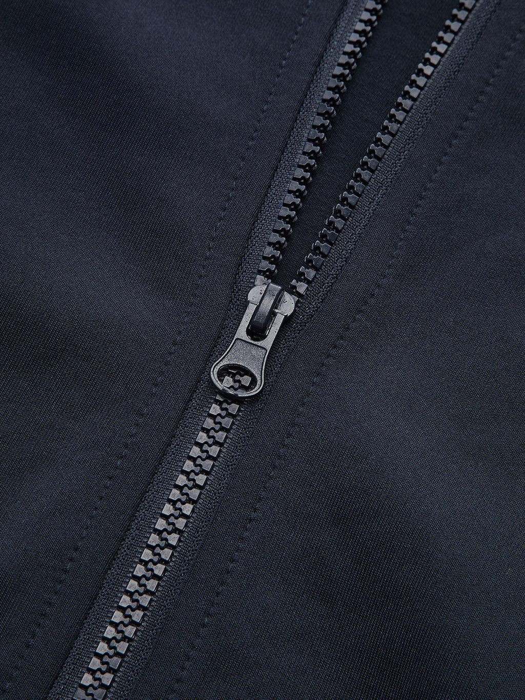 Cropped athletic sweatshirt with black zipper, detailed teeth, and visible precise stitching on dark fabric.