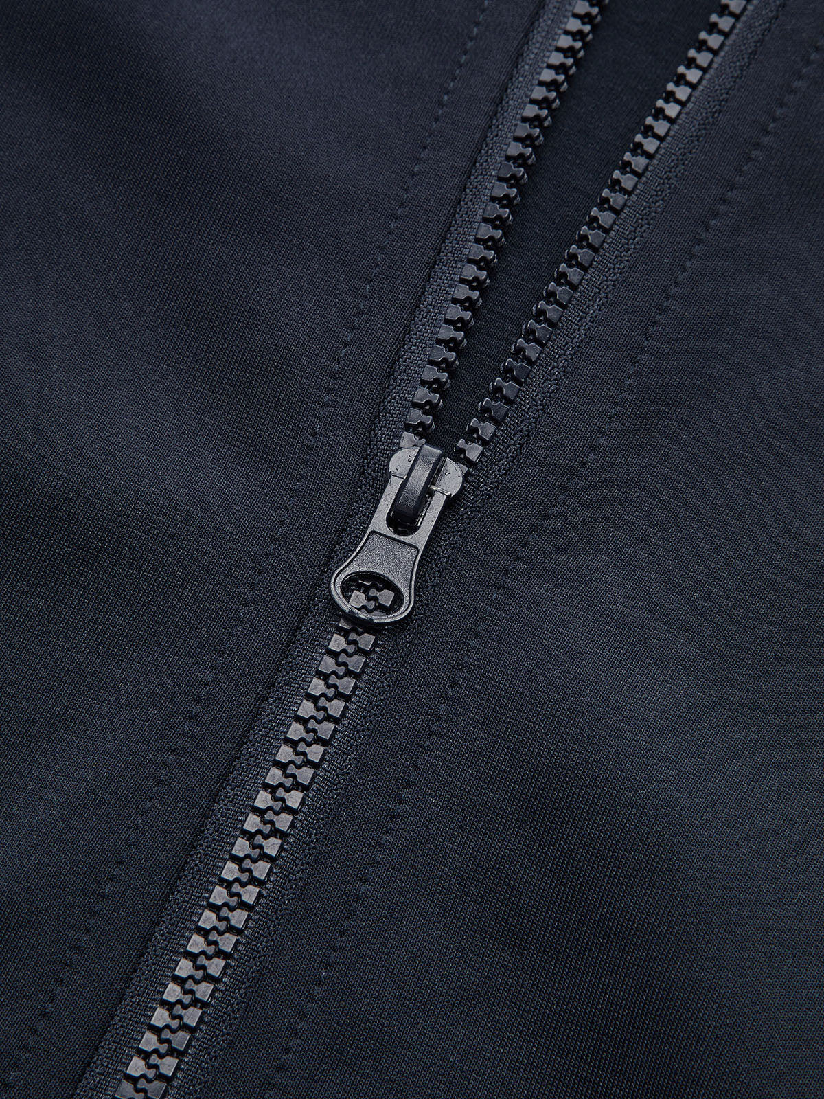 Cropped athletic sweatshirt with black zipper, detailed teeth, and visible precise stitching on dark fabric.