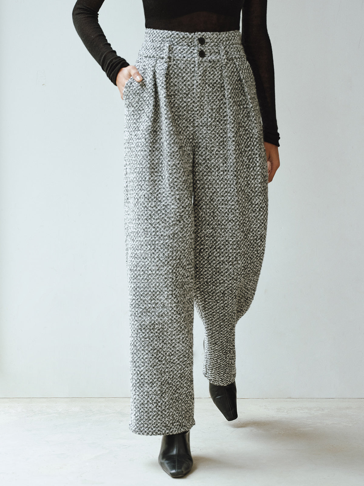 Double waistband wool blend tweed trousers with a fitted black long-sleeve top and pointed-toe shoes.