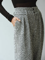 High-waisted, textured grey wool blend tweed trousers with black buttons and a black long-sleeve top.