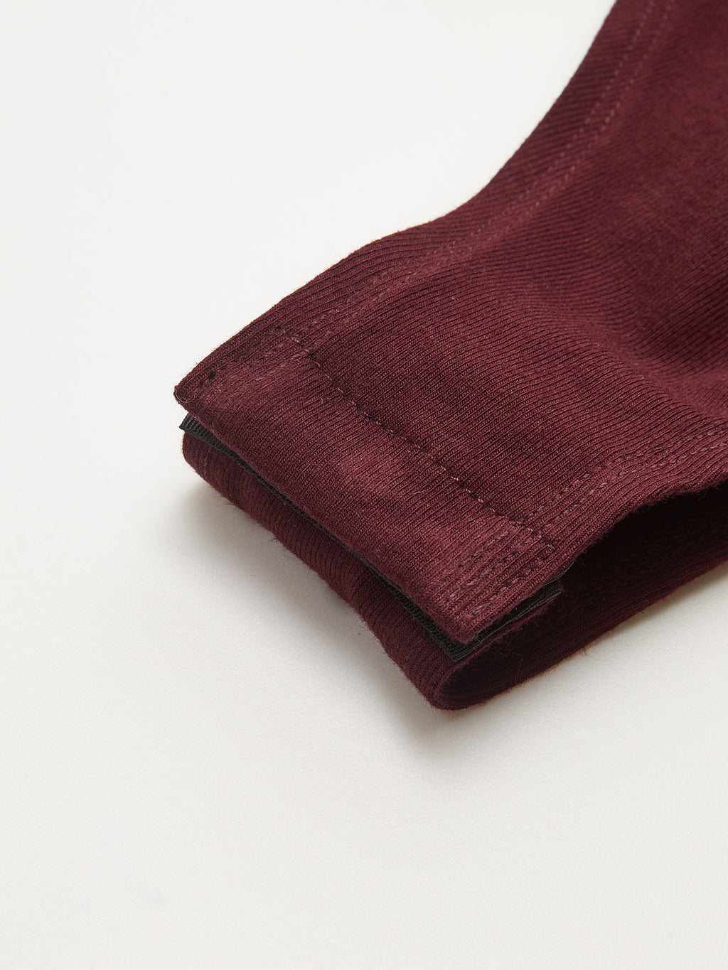 Maroon backless long-sleeve bodysuit cuff features buckled detail, soft textured fabric, precise stitching.