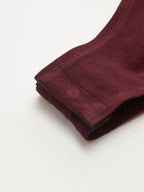 Maroon backless long-sleeve bodysuit cuff features buckled detail, soft textured fabric, precise stitching.