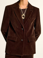 A dark brown velvet shawl collar blazer paired with a black shirt underneath.