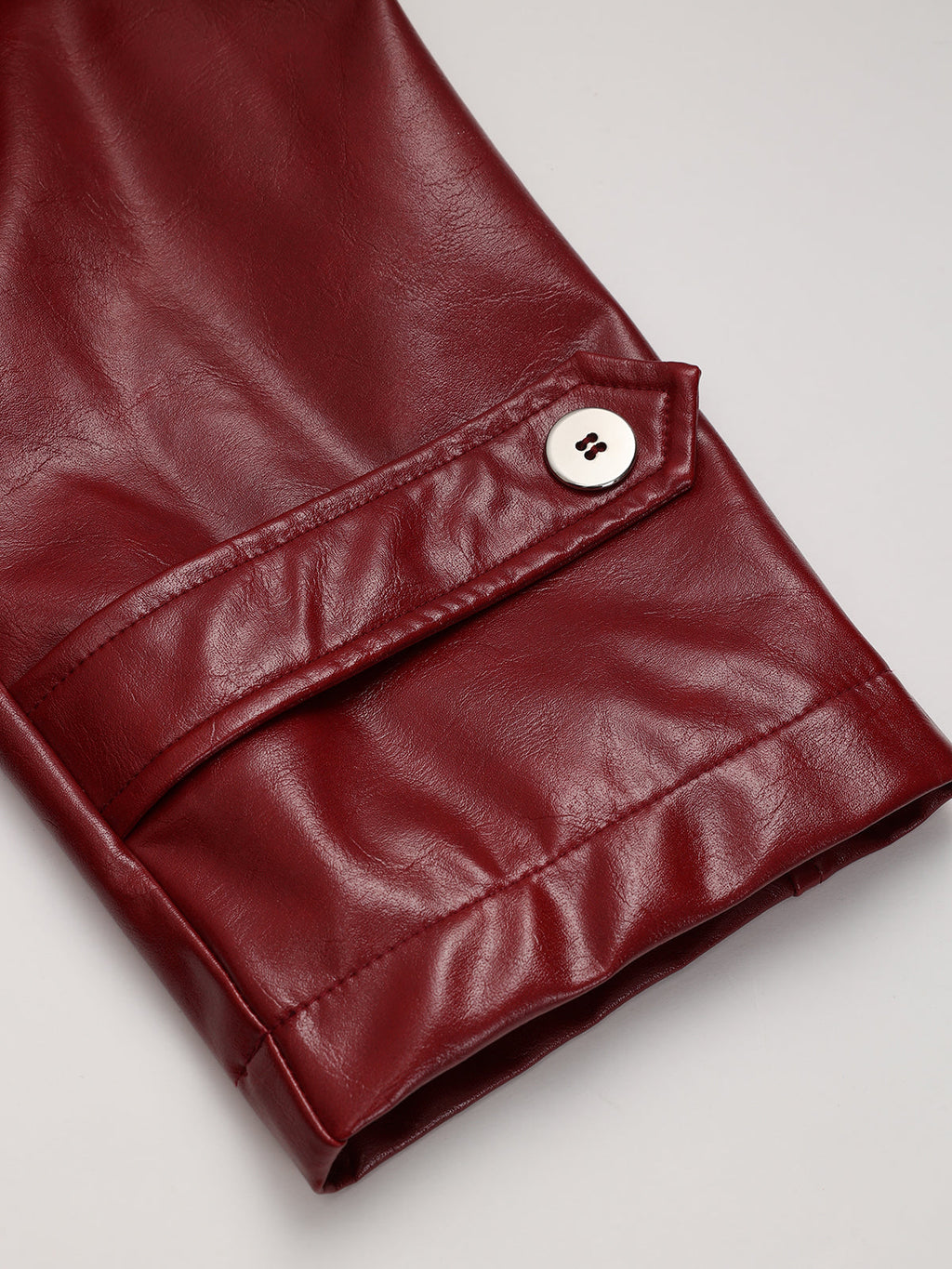 Close-up of a faux leather red-sleeved trench coat with strap and white cuff button.