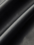 Close-up of black faux leather midi skirt, soft folds highlighting its glossy, textured finish.