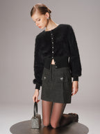 A cropped Faux Mink Cardigan with buttons, a dark textured skirt, and sheer tights.