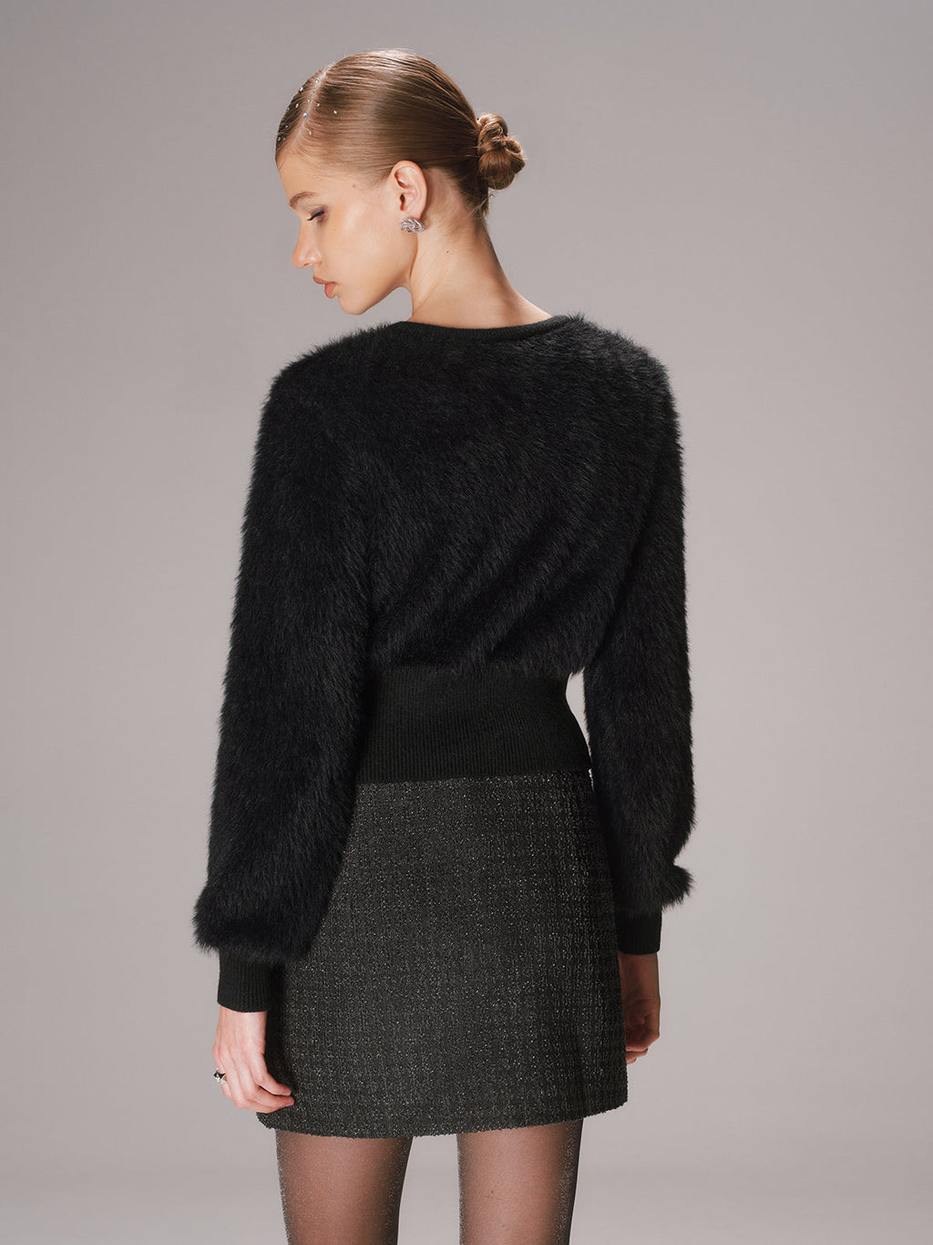 Cropped faux mink cardigan with button-front, worn over a dark textured skirt and sheer tights.
