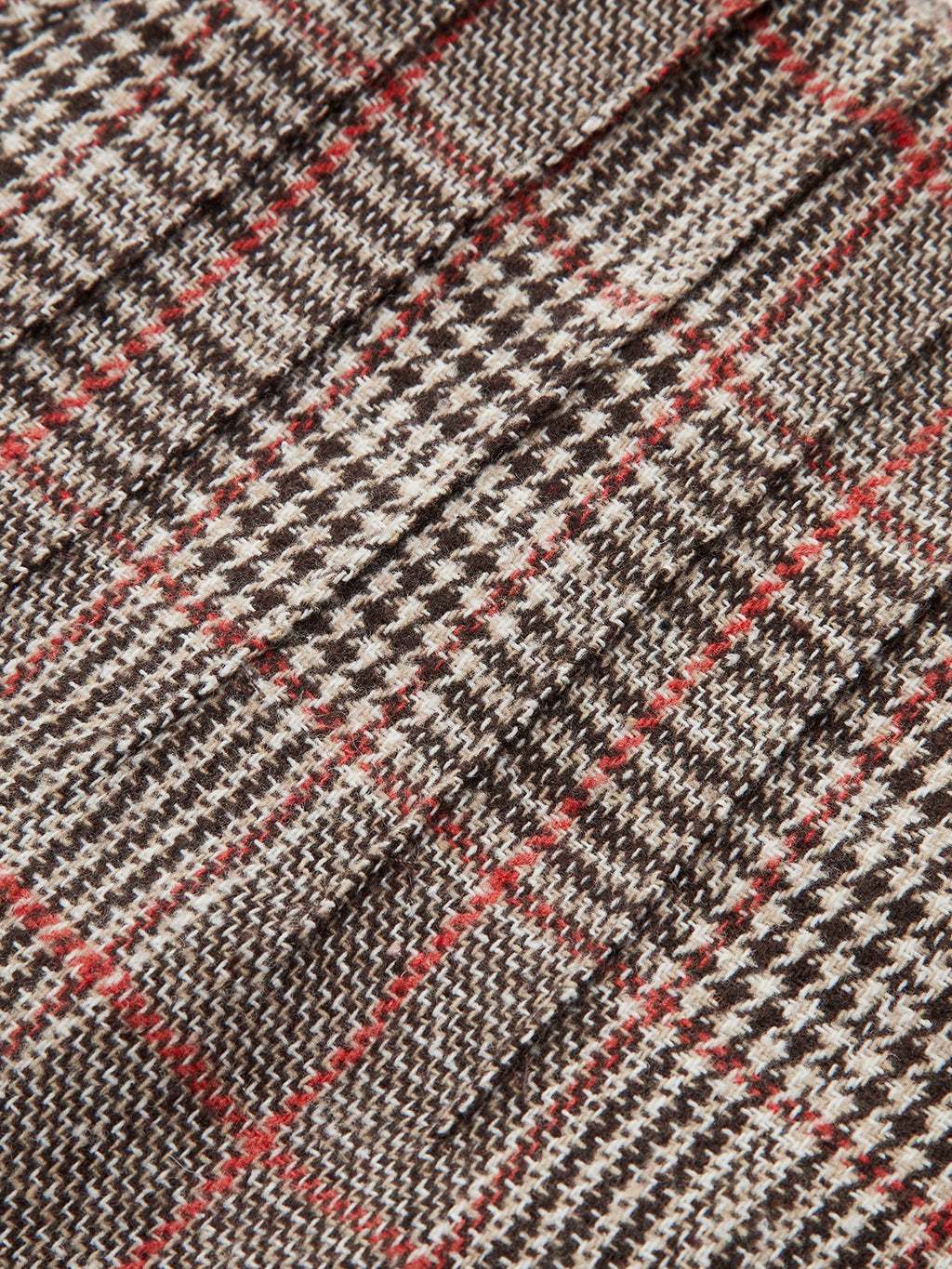 Detailed close-up of brown, black, and white checkered tweed shorts with red accents.