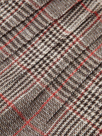 Detailed close-up of brown, black, and white checkered tweed shorts with red accents.