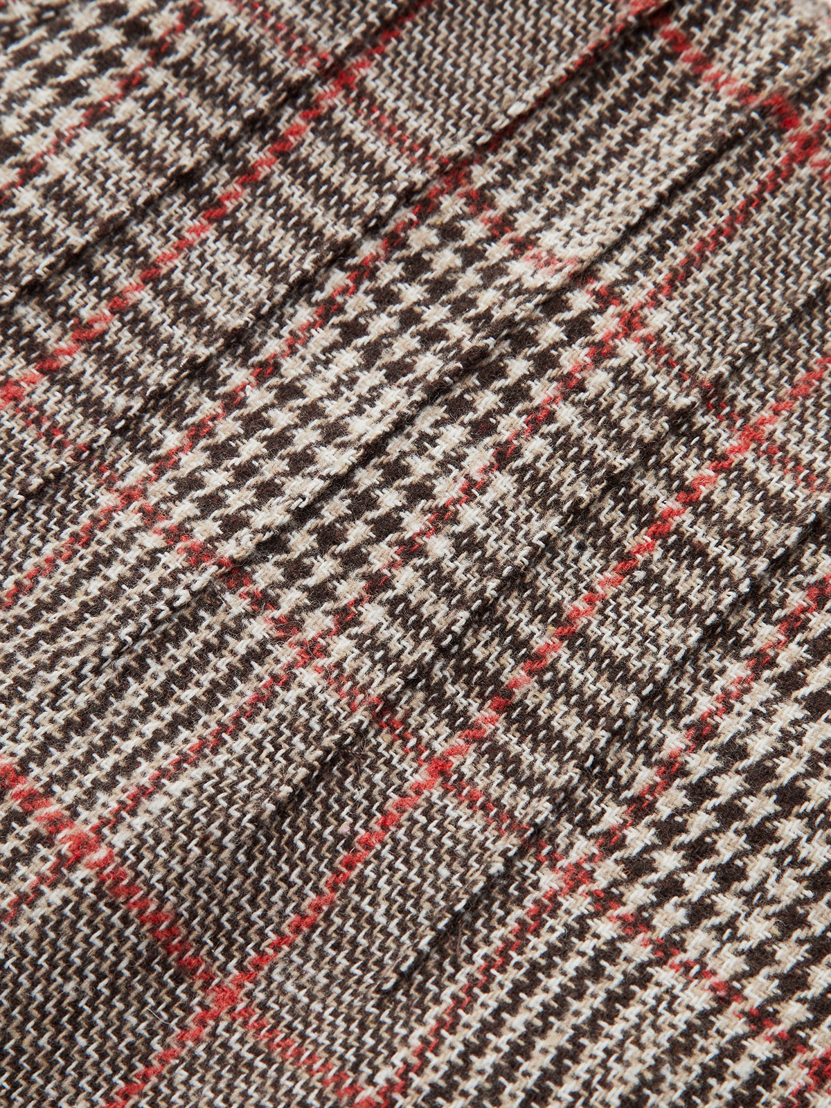 Detailed close-up of brown, black, and white checkered tweed shorts with red accents.