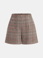 High-waisted tweed shorts with black, white, and red plaid, belt loops, and front pleats.