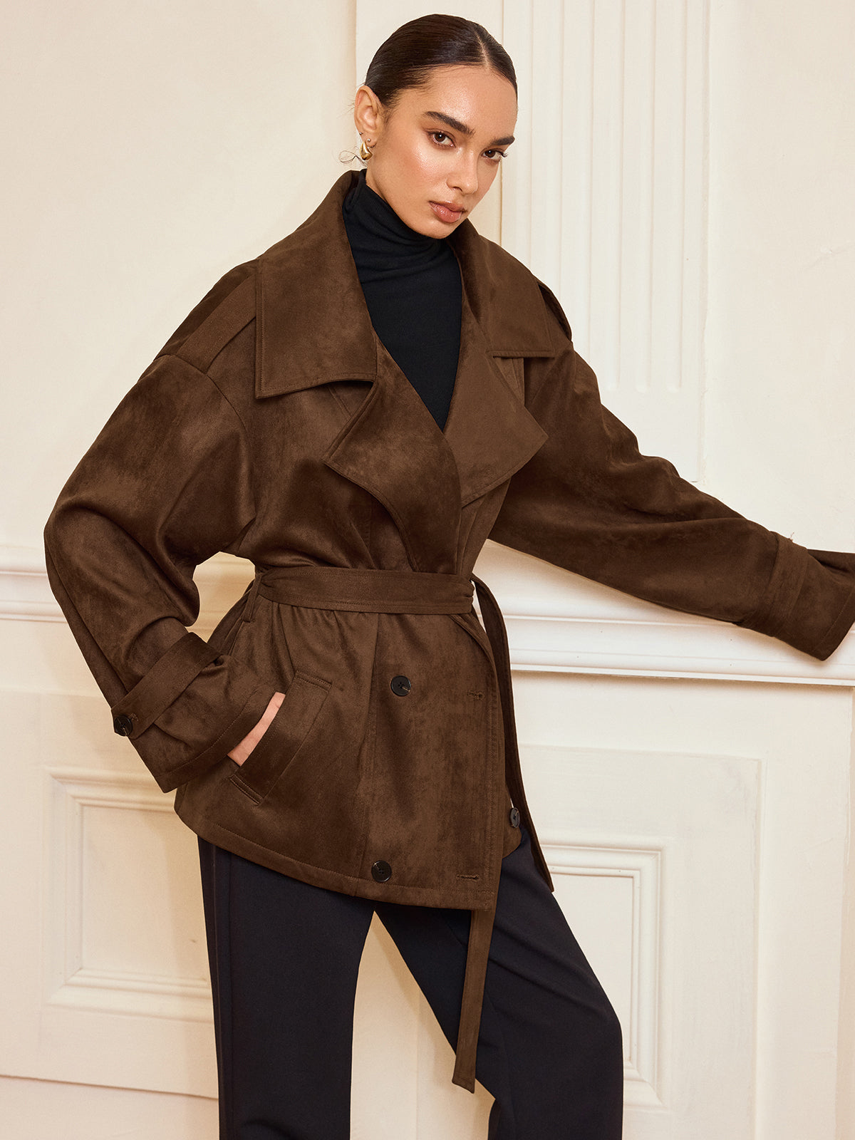 LA FINE FLEUR suede-like trench coat with belt and lapel over black turtleneck, pants.