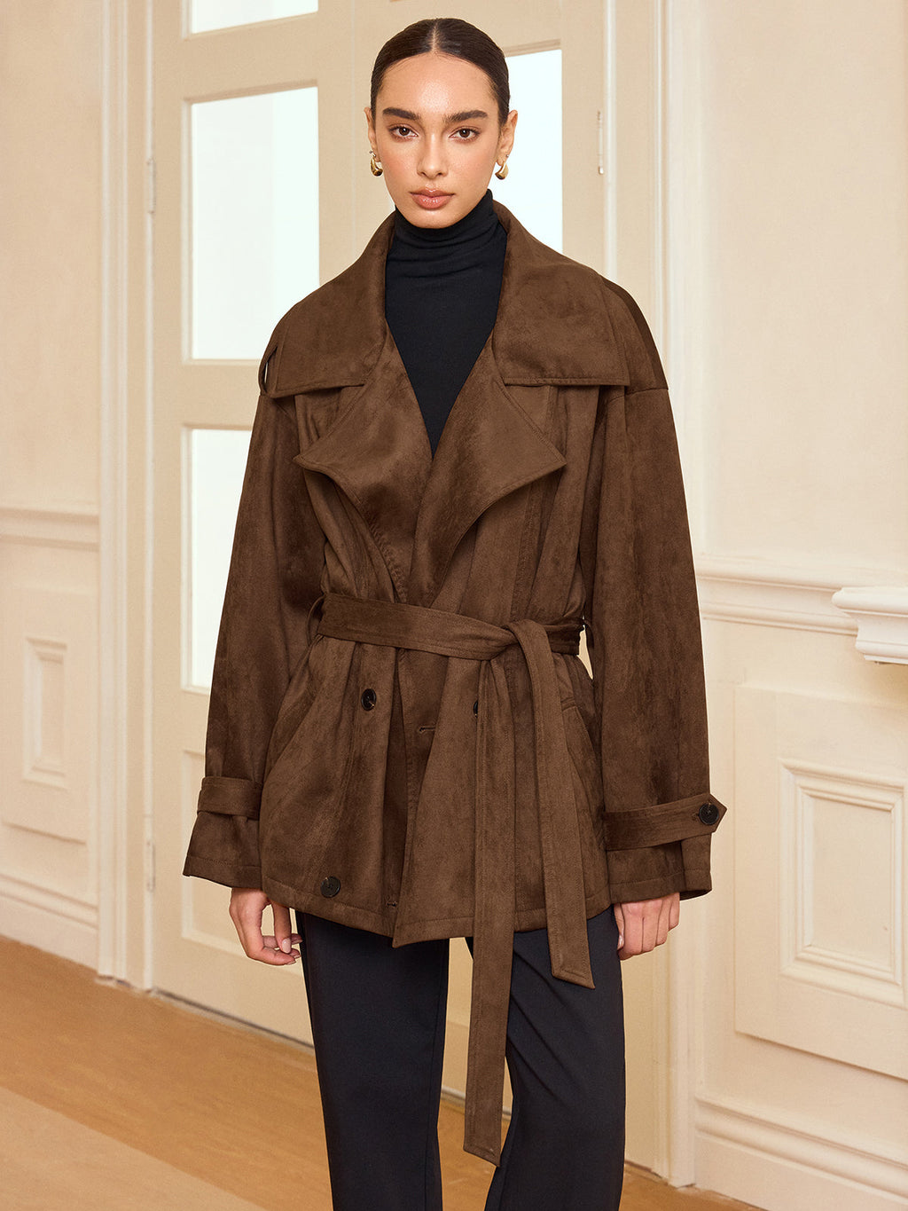 LA FINE FLEUR suede-like trench coat with belt and lapel over black turtleneck and pants.